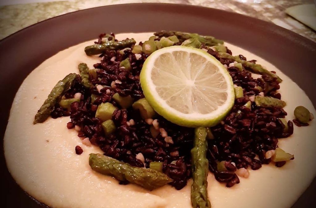 Riso con asparagi su una crema chiara, guarnito con una fetta di limone.