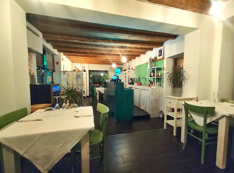 La sala del Green Corner la sera: tovaglie bianche, bancone verde acqua e luci calde.