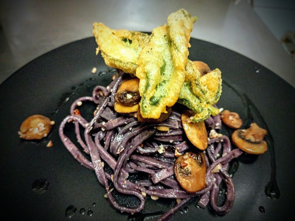 Tagliolini viola ai mirtilli con funghi e fiori di zucca in tempura.